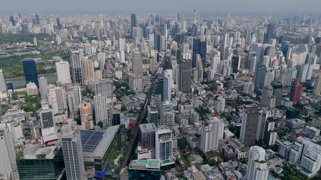 Expansive panoramic views capture the dense urban landscape of Bangkok where towering glass buildings overlook green spaces and busy roads in the daylight