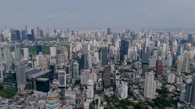 Golden sunlight illuminates the dense skyline of Bangkok where modern architecture reaches towards the clouds in a sprawling metropolitan expanse