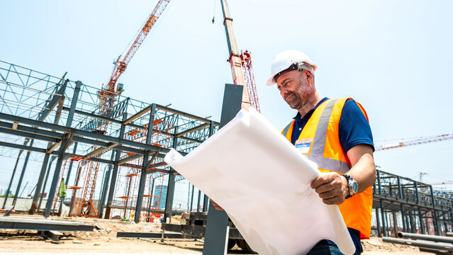 Engineer examining construction blueprint outdoors