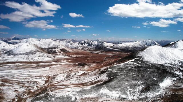 Aerial over bare Tibetan plateau ridges with patchy snow