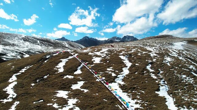 Prayer flag line across a snow patched Tibetan hillside