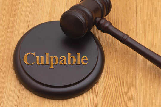 Guilty Culpable Spanish text with a judge gavel and block on wood desk for legal authority