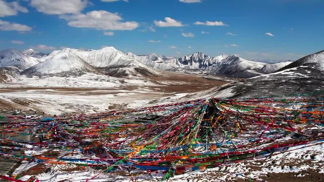 Dense prayer flags framing snowy mountain ranges in Tibet