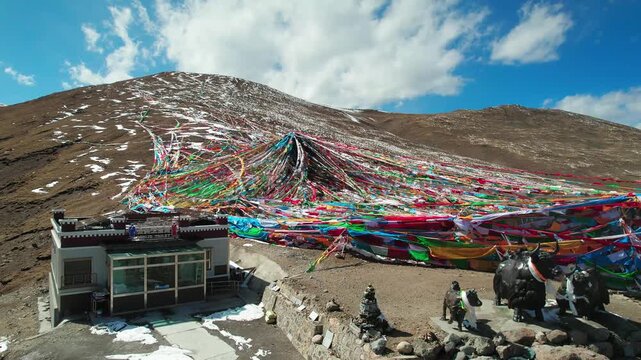 Close aerial around prayer flags beside a small Tibetan hut