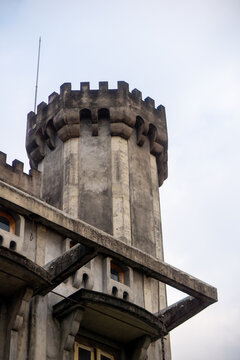 Medieval Style Concrete Castle Tower Architecture Against Overcast Sky. Low angle view of a medieval-style concrete castle tower with battlement parapet wall against a cloudy sky