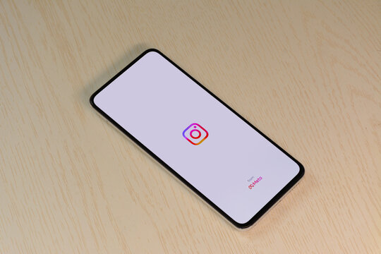 Social media app loading screen on smartphone lying on wooden table