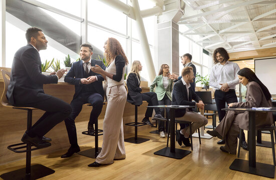 Business team colleagues meeting networking discussion talking. Diverse professionals connect on a coffee break in an office lounge, exchanging ideas. Clear teamwork and collaboration concept.