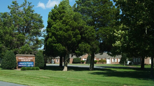 Frederica, Delaware, U.S.A - Sept 9, 2026 -Barratt's Chapel & Museum sign and historic brick building surrounded by trees and landscaped grounds on a sunny day.