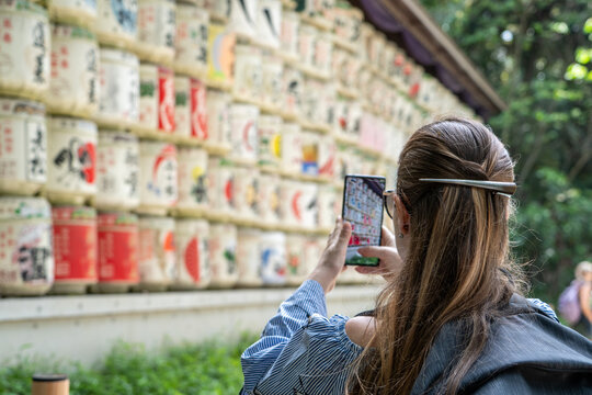 Mujer turista disfrutando su visita por el santuario de Meiji, tomando una fotograf&iacute;a a las ofrendas de contenedores de arroz y sake. En Tokio, Jap&oacute;n