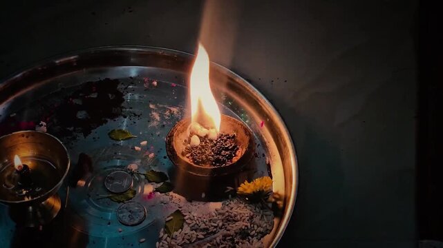 Close up view of burning camphor and oil lamps arranged on a traditional Hindu pooja thali, capturing the deep spiritual essence, devotion, and sacred fire rituals of a Satyanarayan prayer ceremony.
