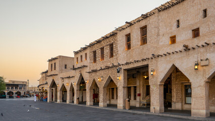 Fototapeta premium Traditional mud-rendered stone architecture and arched corridors of Souq Waqif market at sunset in Doha, Qatar.