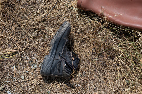 Lost boot abandoned on dry grass, symbolizing solitude, forgotten items, and the remnants of a journey