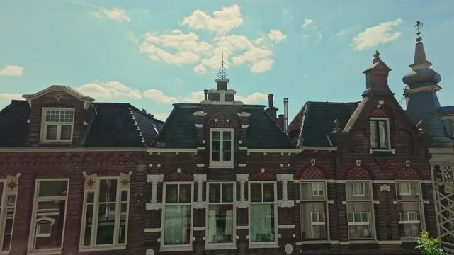 Historic traditional Dutch brick buildings with ornate gables and facades against a blue sky with clouds in the Netherlands