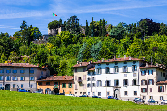 Rocca of Bergamo with the Italian flag flying above its keep, seen from the Parco della Fara