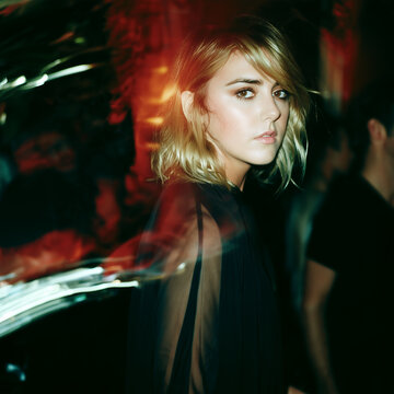 Stylish blonde woman in black dress with dramatic red lighting and motion blur