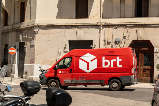 Bari, Italy - Aug 4, 2026: Red BRT delivery van standing at a corner of an old town street with a no entry sign, parked scooters and stone facades in the background