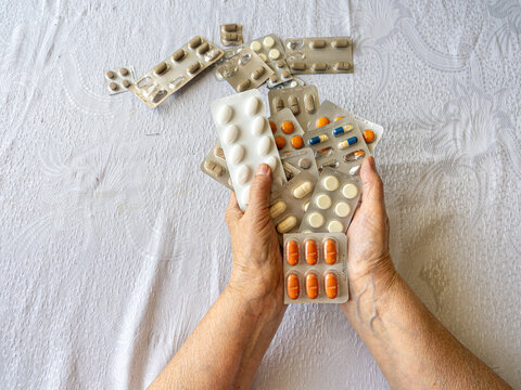 Senior Woman Hands Holding Multiple Medication Blister Packs at Home