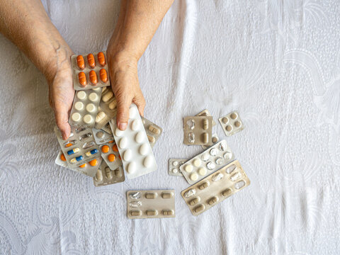 Senior Woman Hands Holding Multiple Medication Blister Packs at Home