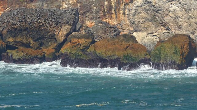 Powerful Ocean Waves Crashing Against Rocky Cliff Coastline with White Spray