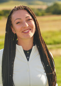 Young Caucasian woman with afro style braids hairstyle, smiling outside on a sunny day - candid portrait