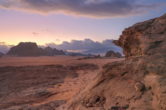 Morning at Wadi Rum desert, orange pink sky above calm red dust arid landscape with rocky formations, scene reminiscent of planet Mars