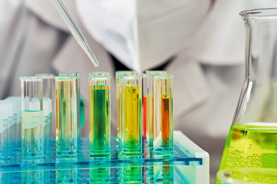 Dropping liquid from pipette to test tubes with samples, closeup detail