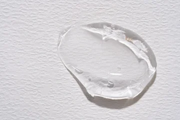 Clear cosmetic gel drop swatch on white paper. Transparent hyaluronic acid smudge, moisturizing face liquid lotion or aloe vera serum sample © IKvyatkovskaya