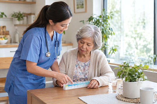 Nurse Helping Senior Woman Organize Medication into Weekly Pill Box at Home Table. Concept of Elderly Medication Management, Homecare and Health Support.