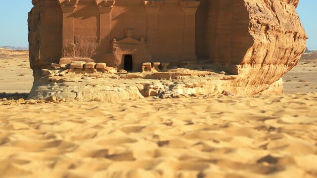 Sand on Saudi Arabia desert, camera moves up to reveal the large structure, Lonely castle - largest tomb at Hegra archaeological site