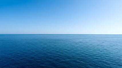 Obraz premium An unobstructed view of deep blue ocean waters meeting a bright cloudless sky at the distant horizon line showing subtle wave patterns across the sea
