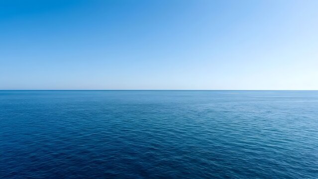 An unobstructed view of deep blue ocean waters meeting a bright  cloudless sky at the distant horizon line  showing subtle wave patterns across the sea