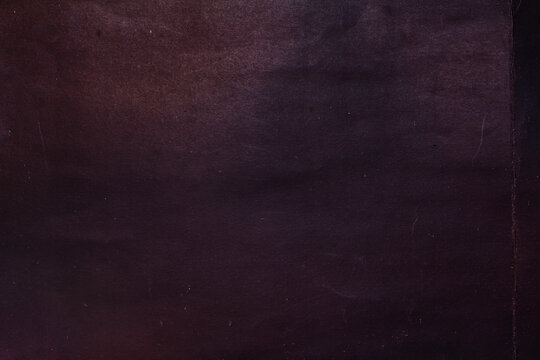 A rough, creased paper surface, with a background of crumpled black paper.