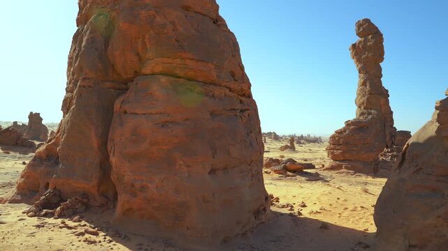 Camera pans over unusual rocky columns formation in Saudi Arabia desert near Al Gharameel, hot sunny day