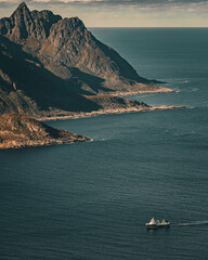 High angle view of vessel navigating along rugged rocky ocean coast under cloudy sky in scandinavia with copy space © Quality by Simon