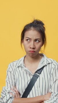 Vertical Screen : Beauty Asia youth serious girl sad unhappy upset negative stressed with boyfriend and deadline work over isolate yellow empty space background with bad mood. Negative face expression
