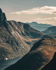 High angle vertical view of layers of mountain ranges and fjord in warm sunlight under cloudy sky in scandinavia with copy space © Quality by Simon