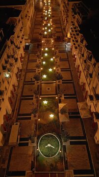 THESSALONIKI, GREECE - DECEMBER 23, 2026: Vertical high-angle aerial drone footage descending over the historic Aristotelous pedestrian street at night. The path is decorated with glowing star-shaped 