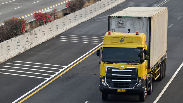 A yellow UD Truck tractor head hauling a trailer