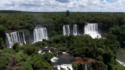 Panoramic aerial view of multiple waterfall cascades framed by dense tropical rainforest © Travelwavi