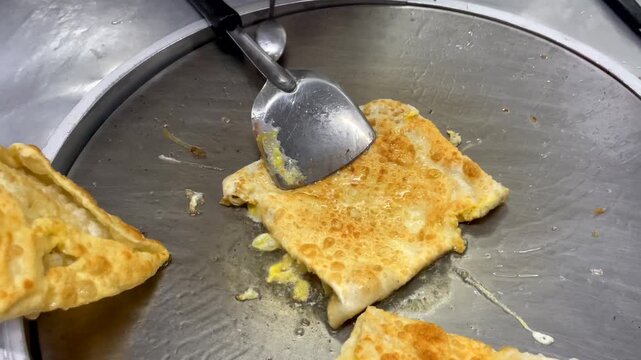 Close-up of traditional Thai roti being cooked with egg and banana on a hot griddle at a street food market in Bangkok, Thailand. Popular local snack and Asian street food.