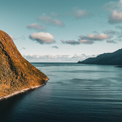 Panoramic aerial drone view of autumn mountain coastline and fjord opening to the ocean under cloudy sky in Senja Norway with copy space © Quality by Simon