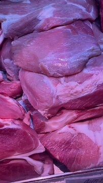 raw beef cuts on display for sale close up, stacked fresh red meat, vertical closeup