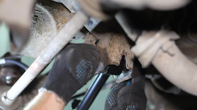Mechanic installs a washer and nut onto suspension arm bolt.