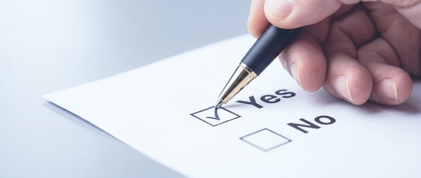 A professional hand uses a pen to check the yes option on an official document during administrative review