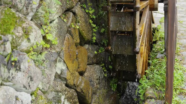 Traditional wooden water wheel spins in stone canal to generate natural power