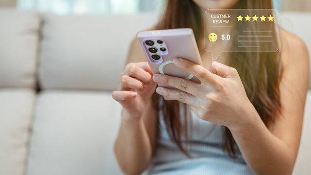 Young woman using smartphone with five-star customer review rating interface, representing online feedback, satisfaction, service quality, mobile technology, and digital consumer experience
