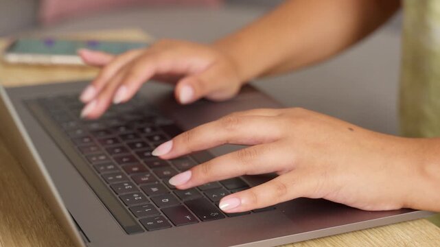 Close up of a business woman's hands typing on a laptop keyboard
