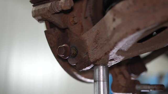 View of car rear brake disc caliper and suspension assembly on lift.