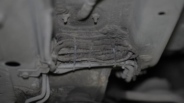 A bundle of automotive wires fixed with zip ties under car.