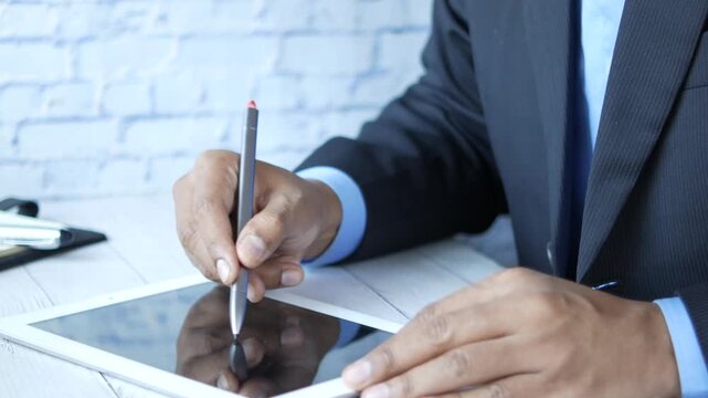 Close up of businessman signing document on digital tablet with stylus
